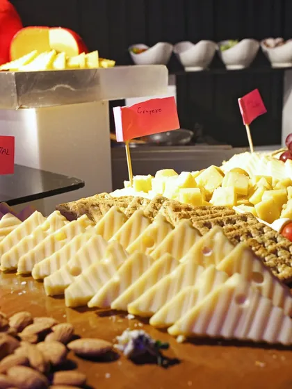 An international cheese board featuring varieties like Emmental and Gouda, served with almonds and crackers for a perfect pairing of textures and flavours.