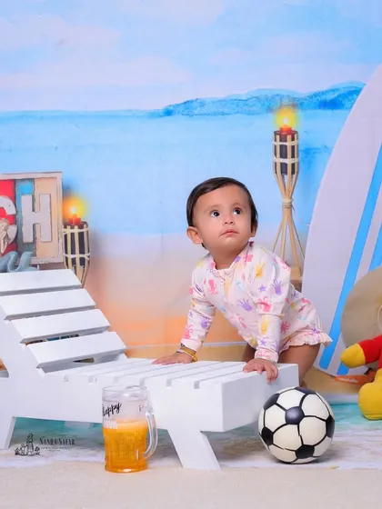 Trying to stand and explore the beach set. This photo captures a key milestone moment of a baby learning to pull themselves up, set against a fun backdrop.
