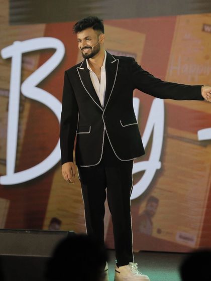 A client owning the stage in our custom black suit with distinctive white piping detail. This is how we tailor a classic black suit to reflect a client's unique personality and flair.