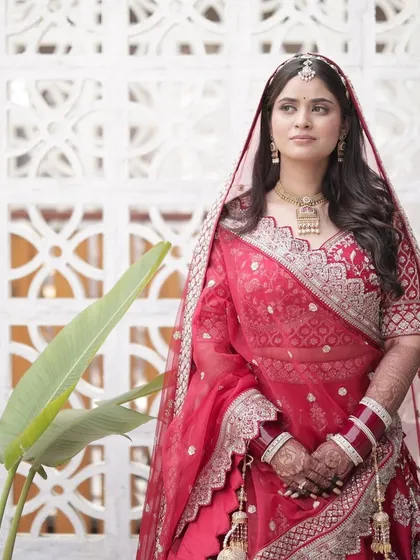 A stunning portrait of the bride in her traditional red lehenga, looking like a vision of grace and beauty on her wedding day.