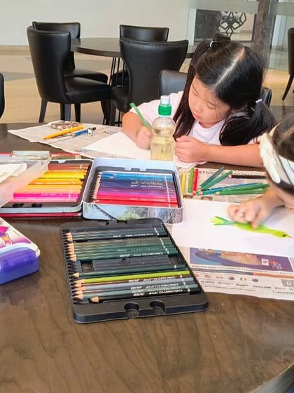 A wide shot of the parrot drawing class, showing students focused on their work with all the necessary art supplies at hand.