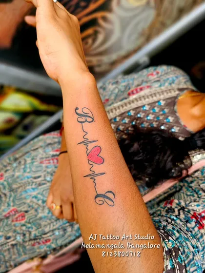 A heartbeat lifeline tattoo connecting the initials 'B' and 'L' with a heart in the middle.