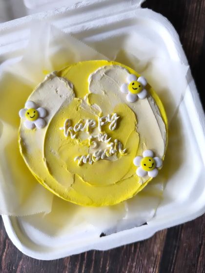 This bright yellow bento cake is designed to spread happiness. It's decorated with cheerful smiley-faced flowers and a message celebrating a five-month anniversary.