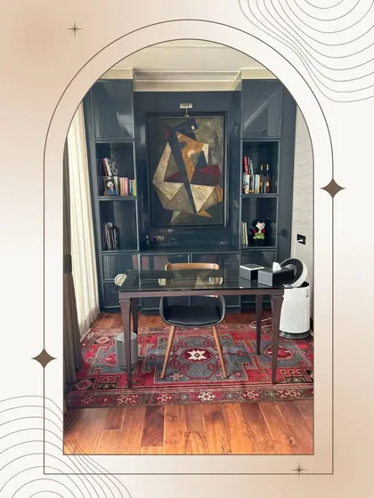 A study area integrated within a master bedroom suite. The dark, high-gloss cabinetry provides ample storage and a sophisticated backdrop for the workspace, which is defined by a classic Persian rug.