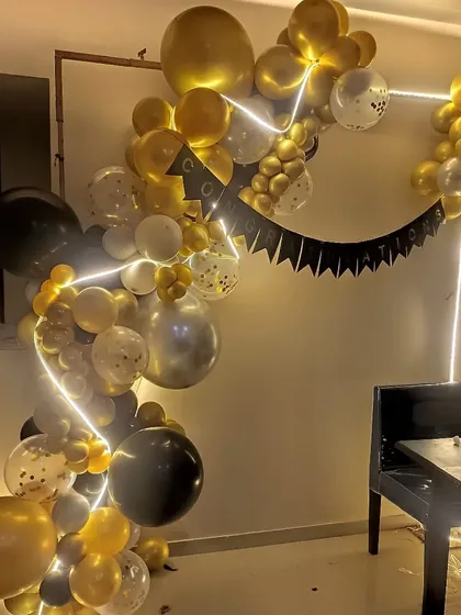 A stylish black, white, and gold balloon garland with LED strip lights. This modern decoration adds a cool, glowing effect to any room.