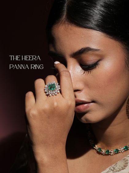 The Heera Panna ring, worn by a model. The magnificent Ascher-cut emerald, framed by round-cut diamonds, truly owns the spotlight in this statement piece.