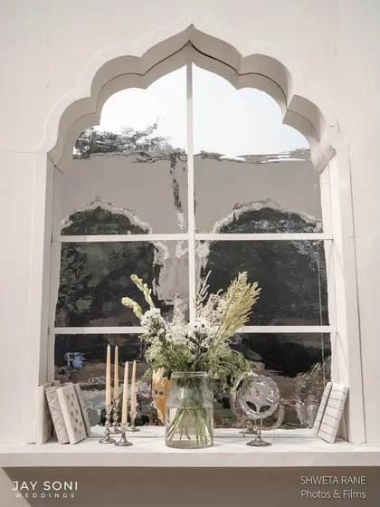A beautifully styled windowsill within the lounge, featuring a vase of wildflowers, antique-style books, and candles, creating a charming vignette.