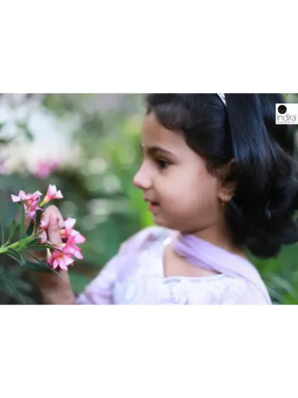 A side profile of the same girl admiring the flowers. This shot highlights her delicate features and the peacefulness of the moment, creating a soft and dreamy child portrait.