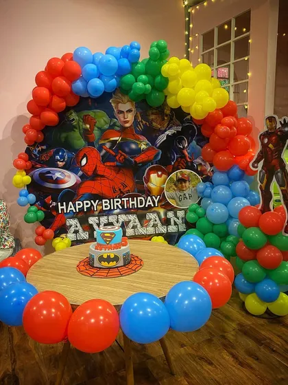 Assembling the mightiest heroes for an Avengers-themed birthday. The decor features a personalized backdrop with all the main characters and a life-sized Iron Man cutout.