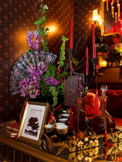 A corner of the lounge, featuring a tray with Japanese-style decanters, a fan, and floral arrangements.