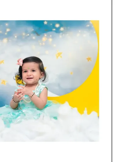 A lovely portrait of a smiling baby girl sitting amidst the clouds in a moon-and-stars themed session. The soft lighting and gentle colors give the photo a dreamy quality.