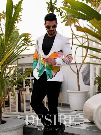 Surrounded by greenery, the vibrant colors of the butterfly-print blazer truly pop. This is a statement piece designed for memorable summer events.