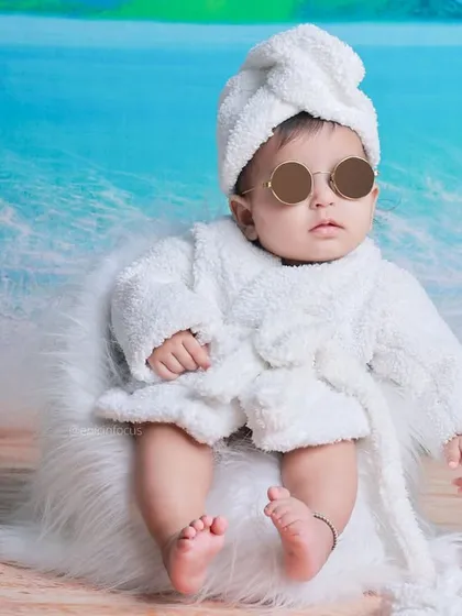 The epitome of cool. A baby in a robe and sunglasses brings a humorous and stylish vibe to this beach-themed studio shoot.