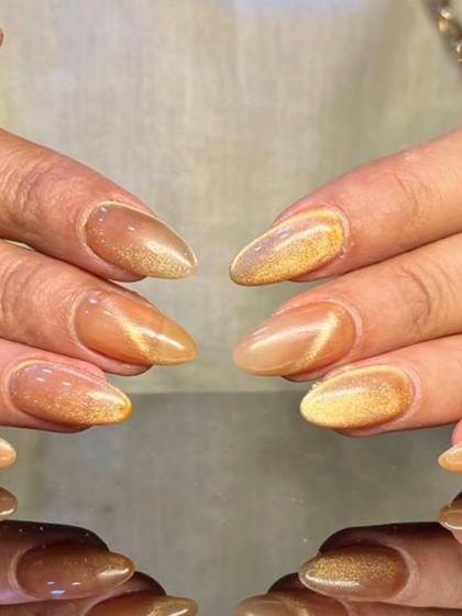 A beautiful golden-brown cat-eye effect on almond-shaped nails, giving a warm and luxurious tiger-eye stone look.