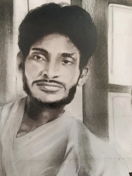 A close-up of the finished charcoal sketch, showing the shading and detail used to bring an old photograph of a young man back to life.