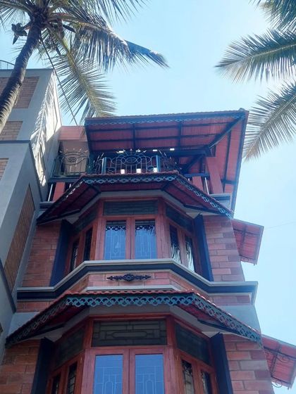 A low-angle shot of the home's facade, emphasizing its verticality and the intricate details of the bay windows and rooflines against the sky.