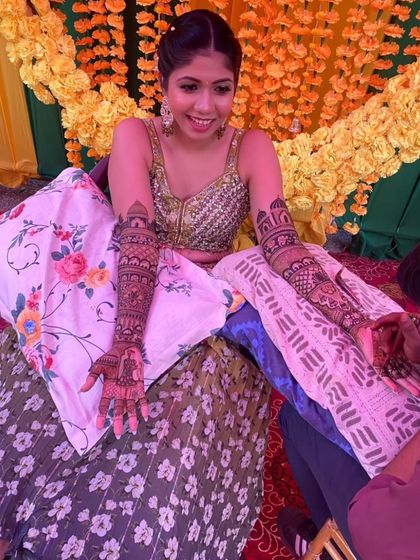 A behind-the-scenes shot of the mehendi application in progress, showing the bride's patience and excitement.