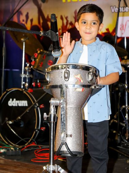 A young percussionist on stage, illustrating the joy and confidence that early music education can bring.