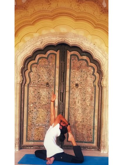 Eka Pada Rajakapotasana (One-Legged King Pigeon Pose) against a stunning architectural backdrop.