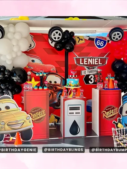 A Disney Cars themed party, featuring Lightning McQueen and friends, with gas station props and a red, black, and white balloon arrangement.