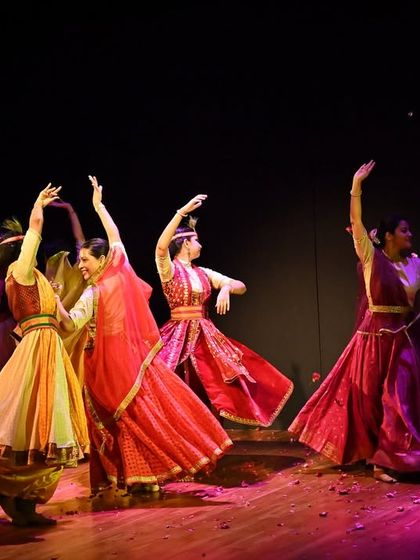 A vibrant group performance celebrating the festival of Holi. The stage is filled with color and energy, capturing the festive spirit through dance.