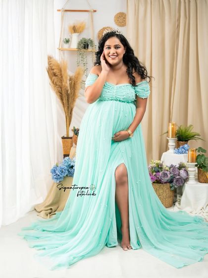 The mint gown's slit and flow are highlighted in this elegant pose, set against a soft boho backdrop.