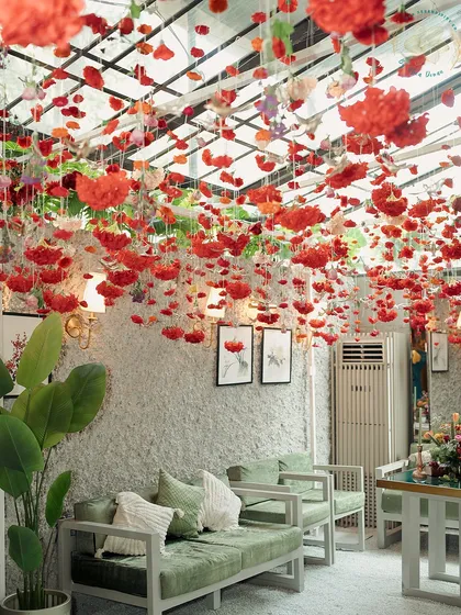 A room transformed by a ceiling of floating red carnations. This immersive floral installation created a bold and romantic atmosphere for a Mehndi party.