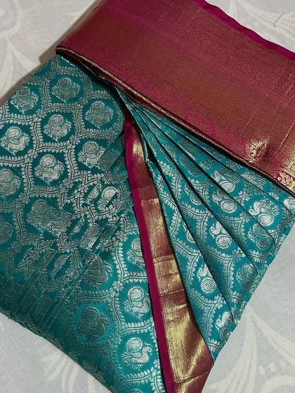 A teal blue saree with silver brocade work, a stunning piece for any party.