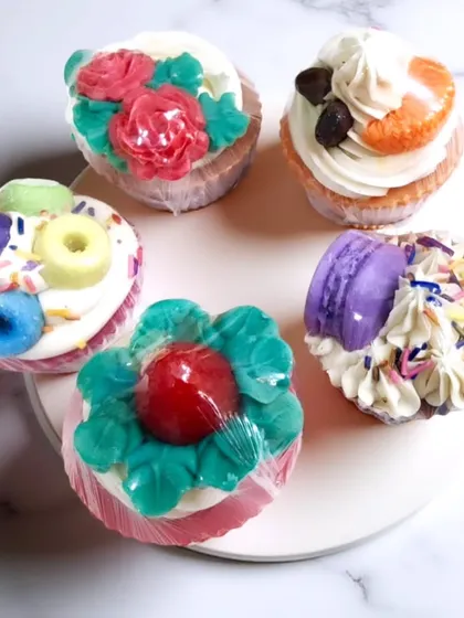 These are my cupcake soaps, and they are almost too cute to use. Each one is handcrafted with a piped frosting top and unique decorations like tiny macarons, roses, or coffee beans, making them a delightful and whimsical treat for your skin.