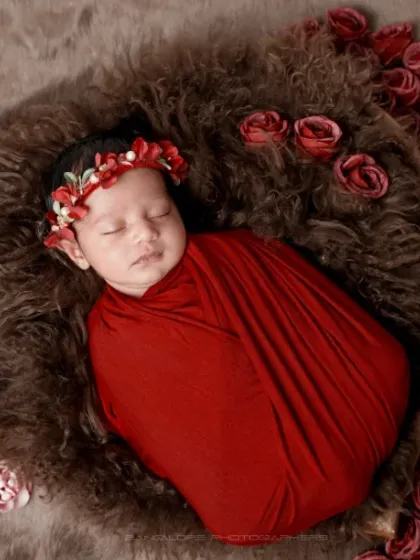 A rose among the roses. This setup features a cascade of red roses next to the sleeping baby, creating a rich and romantic portrait.