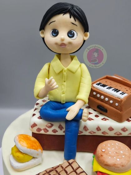 A custom figurine for a young man who loves music and food, featuring a miniature harmonium and his favorite snacks like vada pav and burgers.