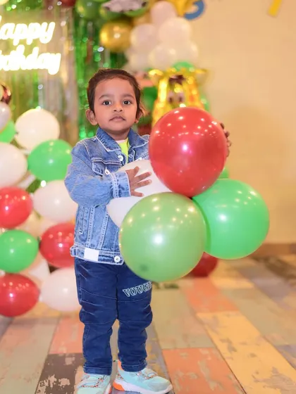A little boy holding balloons, ready to party. The simple joy of balloons is a timeless part of any childhood celebration.