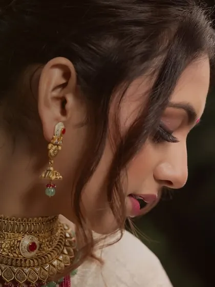 A detailed profile shot focusing on the intricate design of the gold choker and jhumka earrings.