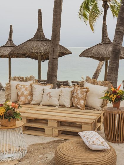 Another view of the rustic beach lounge seating, set under the natural shade of palm trees.
