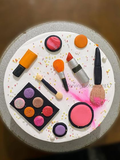 A top-down view of the makeup-themed cake, showing the arrangement of the hand-sculpted fondant lipstick, brushes, and nail polish.