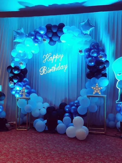 A cool blue and black Boss Baby theme for a 4th birthday, featuring a balloon ring, a light-up number, and a glowing character cutout.
