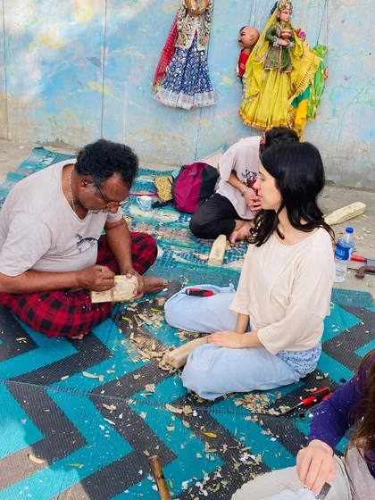 Teaching is a very important part of my work. Here, I am guiding a student during a wood carving workshop, showing her how to shape the puppet's head using traditional tools and techniques passed down through generations.