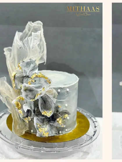 An example of my couture cake work, this design features a soft grey frosting naturally colored with black charcoal. It is decorated with abstract, handcrafted rice paper sails and flecks of edible gold leaf, offering a modern and sophisticated aesthetic without fondant.
