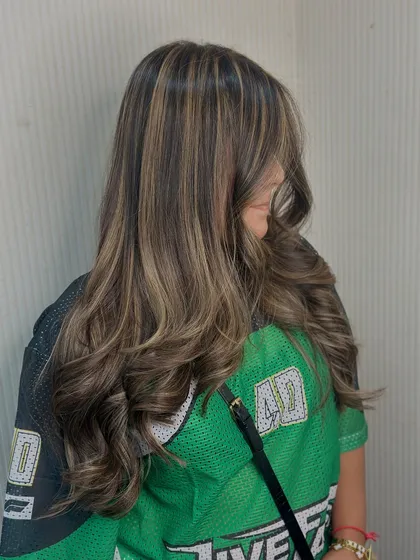 A side profile showing how our balayage technique creates depth. The highlights are woven through the hair for a seamless, natural looking blend.