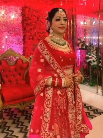 A radiant bride in a bright red lehenga with delicate gold embroidery. This is a perfect example of a classic bridal look that is both elegant and eye-catching.