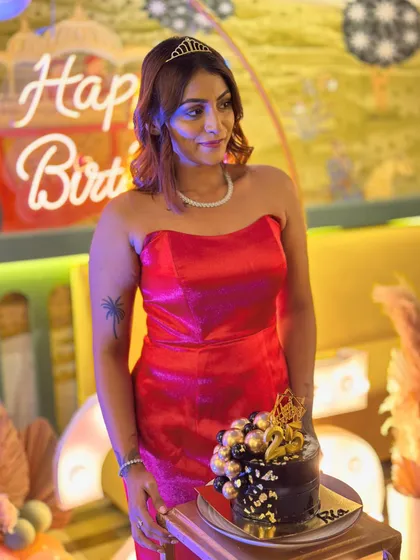 A candid moment with my birthday cake. The simple elegance of the red gown is complemented by a delicate necklace and a tiara for a fun, celebratory touch.