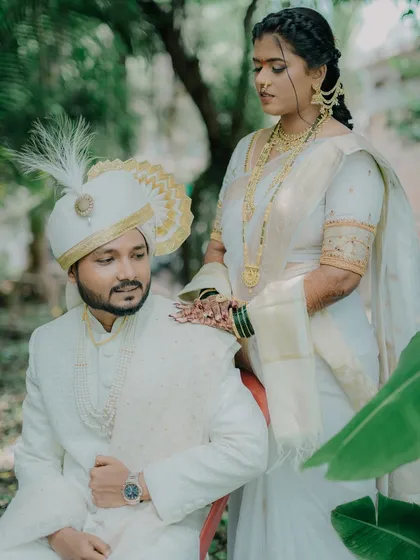 A beautifully composed shot with the bride standing behind her seated groom. Her hand on his shoulder shows support and affection, creating a regal and intimate portrait.