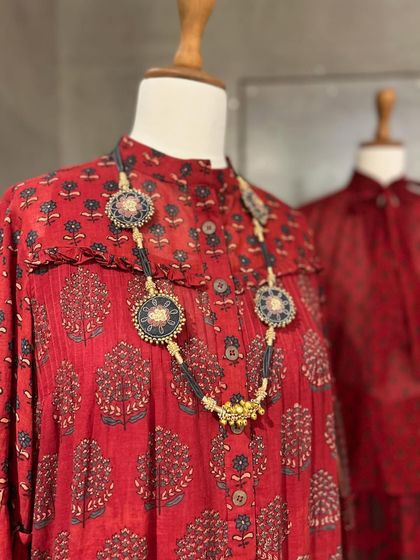 A close-up of a red printed dress with a ruffled collar, highlighting the intricate traditional print.
