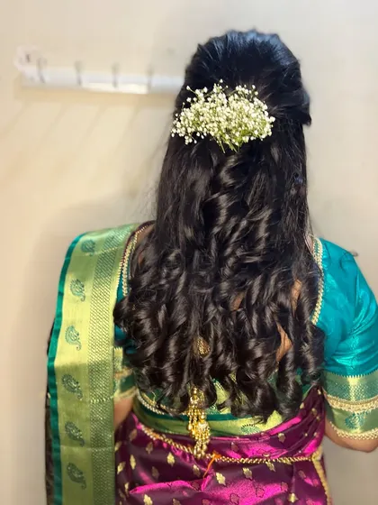 Cascading curls for an engagement bride. The half-up style is decorated with baby's breath for a romantic and delicate finish.