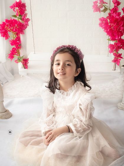 A beautiful solo portrait of the older sister from the family session, smiling sweetly in her lovely white lace dress.