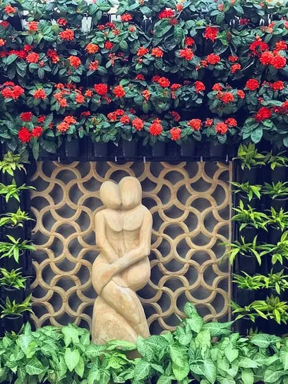 A vertical garden can be a work of art. For this home, I designed a living wall that frames a beautiful sculpture, using flowering red Ixora plants to create a stunning, high-impact centerpiece that feels both natural and elegant.
