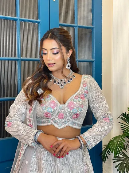 A chic and modern reception look. This model wears a grey lehenga with floral embroidery, paired with a unique zircon necklace featuring black stones for a touch of contemporary drama.