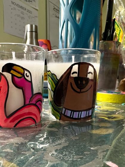 A fun set of candles, one with flamingos and the other with a happy dog.