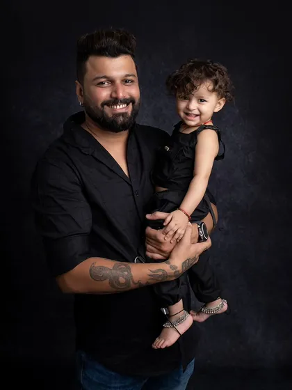 A sweet moment between a father and his child, both smiling for the camera.
