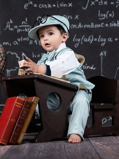 A baby boy in a suit looks up, as if thinking hard about his studies, in this adorable scholar-themed shoot.